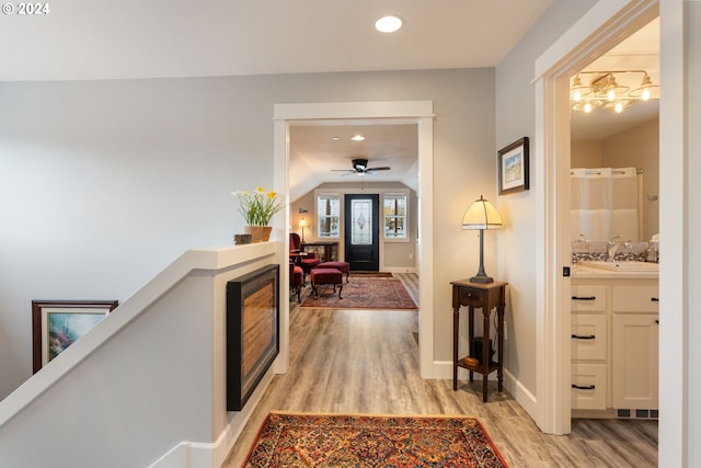 hall featuring sink, vaulted ceiling, and light wood-type flooring