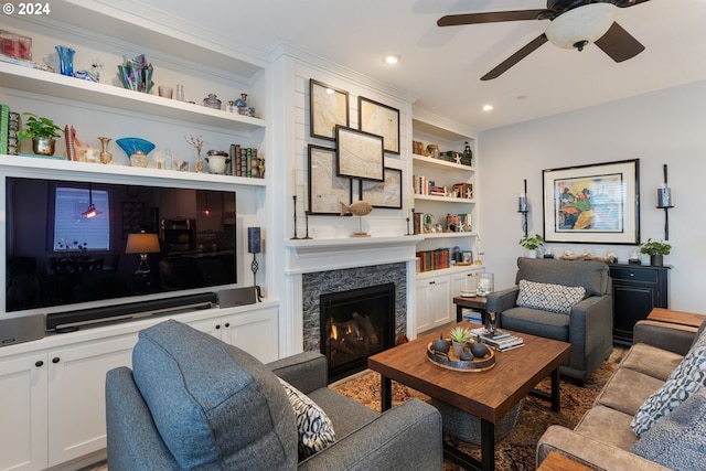 living room featuring built in features, ceiling fan, ornamental molding, and a premium fireplace