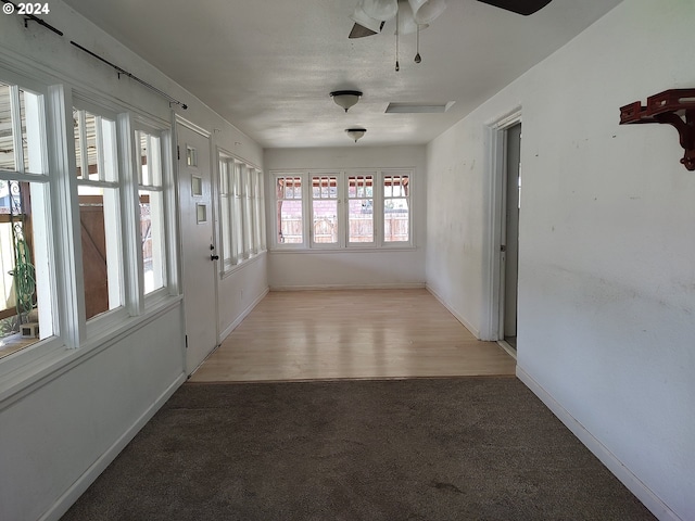 unfurnished sunroom with ceiling fan