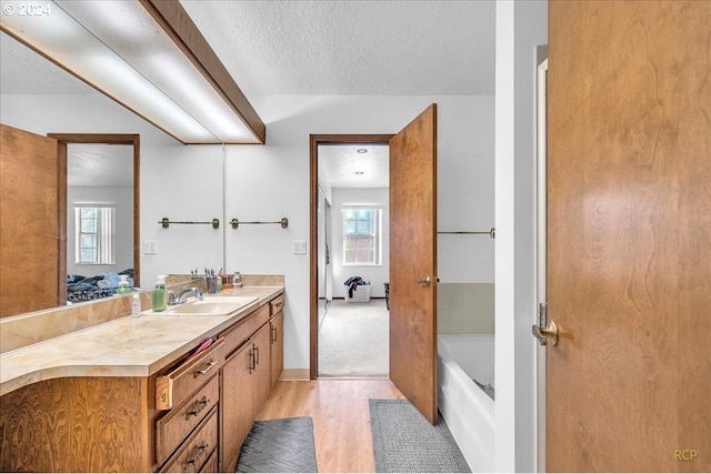 bathroom featuring vanity, a textured ceiling, a bathtub, and wood-type flooring