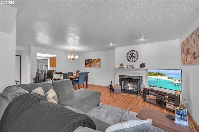 living room with a notable chandelier, a textured ceiling, wood-type flooring, and a fireplace