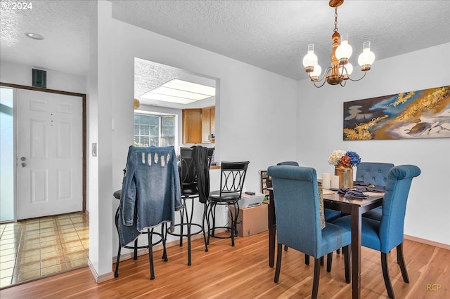 dining area featuring a chandelier, a textured ceiling, and light wood-type flooring