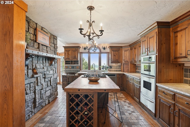 kitchen featuring wooden counters, a kitchen island, an inviting chandelier, stainless steel appliances, and a warming drawer