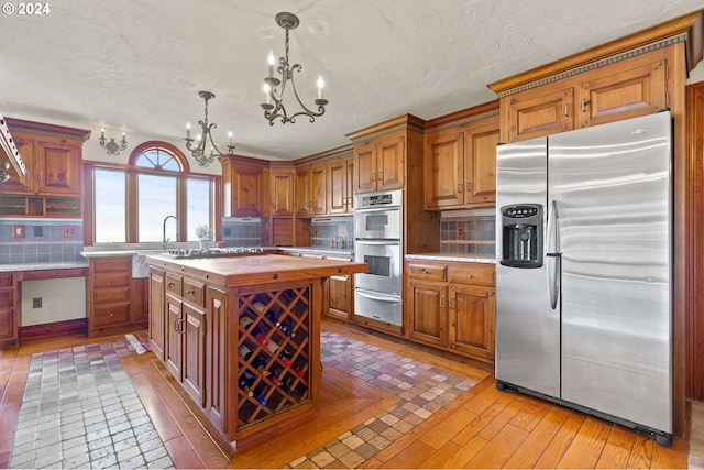 kitchen featuring backsplash, a chandelier, stainless steel appliances, wood counters, and a warming drawer