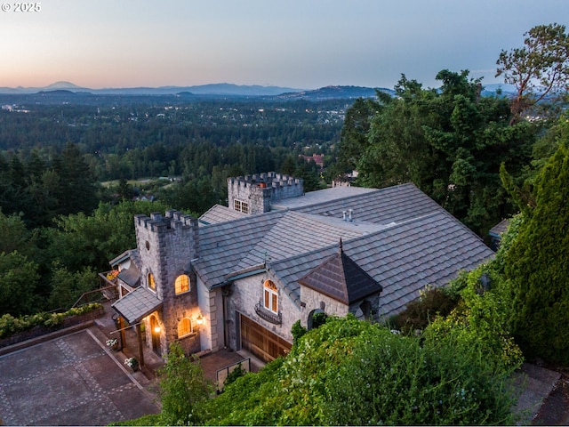 aerial view at dusk featuring a forest view and a mountain view