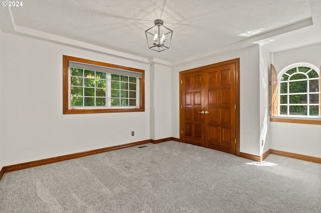 unfurnished bedroom with multiple windows, carpet flooring, baseboards, and a chandelier