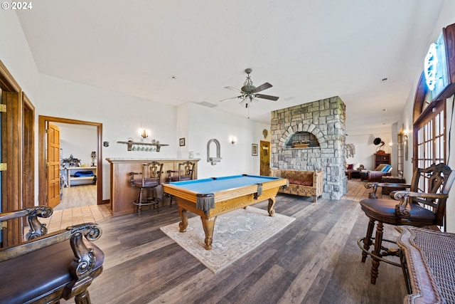 playroom with billiards, wood finished floors, ceiling fan, a bar, and a stone fireplace