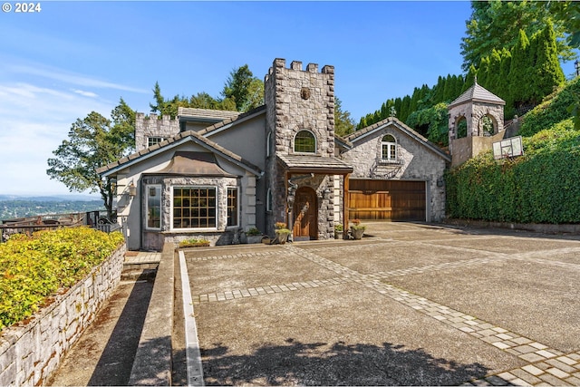 view of front of property with a tiled roof, concrete driveway, stucco siding, a garage, and stone siding