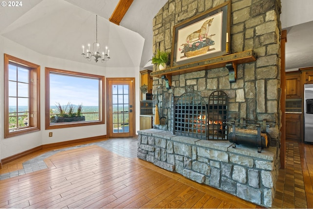 living area with baseboards, lofted ceiling, hardwood / wood-style floors, a fireplace, and an inviting chandelier