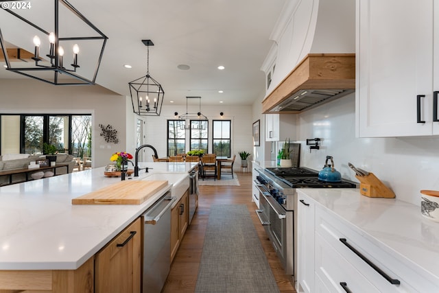 kitchen featuring appliances with stainless steel finishes, a healthy amount of sunlight, white cabinets, and a large island with sink