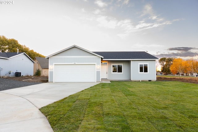 ranch-style house featuring a garage, cooling unit, and a yard