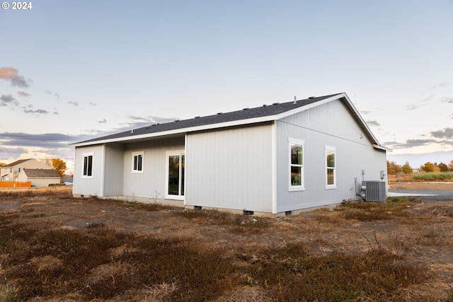 back house at dusk featuring central air condition unit