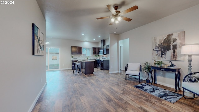 living room with wood-type flooring, ceiling fan, and sink