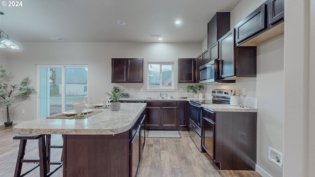 kitchen featuring a wealth of natural light, a kitchen island, pendant lighting, and appliances with stainless steel finishes