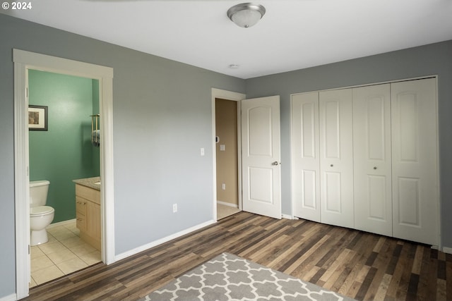 bedroom with a closet, dark hardwood / wood-style floors, and connected bathroom