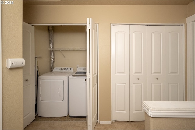 laundry room with light colored carpet and washer and dryer