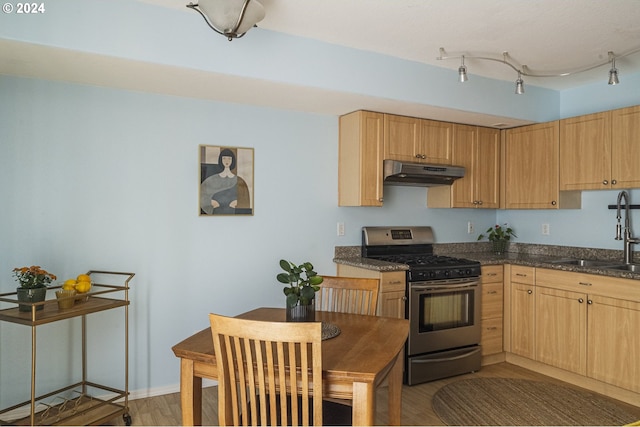 kitchen with sink, dark wood-type flooring, rail lighting, light brown cabinetry, and gas stove