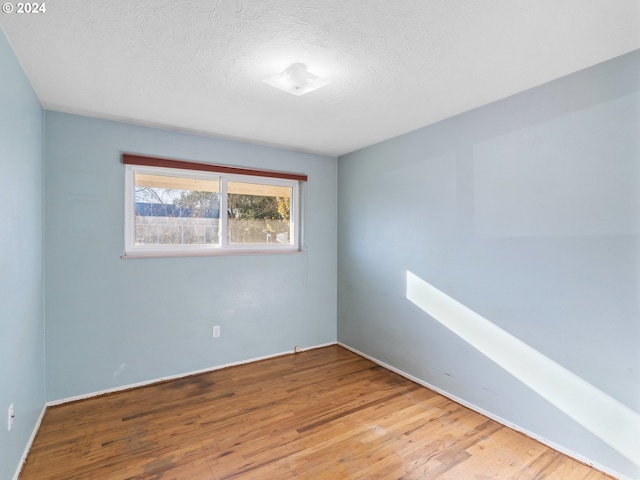 spare room with light wood-type flooring and a textured ceiling