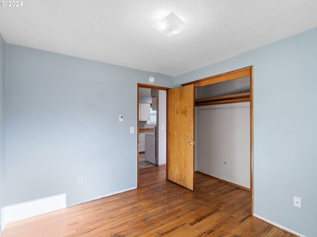 unfurnished bedroom with a textured ceiling, a closet, and dark hardwood / wood-style floors