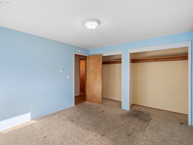 unfurnished bedroom with carpet flooring and two closets