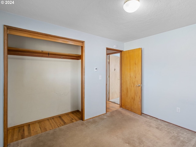 unfurnished bedroom featuring a textured ceiling, light colored carpet, and a closet