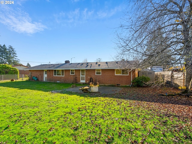 rear view of property with a storage unit, a yard, and a patio