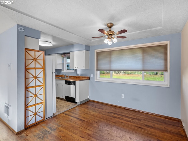 kitchen with white cabinets, a textured ceiling, sink, light hardwood / wood-style flooring, and dishwasher