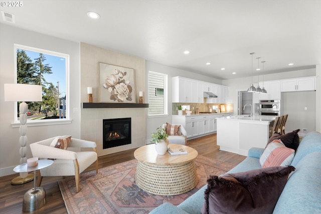 living room with sink, light hardwood / wood-style floors, and a tile fireplace