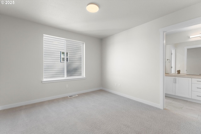 spare room featuring light colored carpet and sink