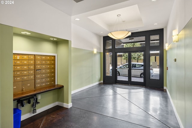 entryway featuring a high ceiling, a mail area, and a tray ceiling