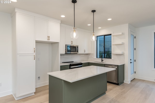 kitchen with light stone countertops, stainless steel appliances, sink, white cabinets, and a center island