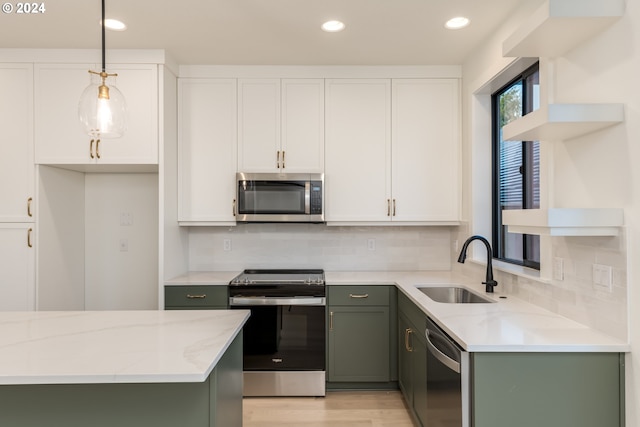 kitchen with green cabinets, hanging light fixtures, light stone countertops, white cabinetry, and stainless steel appliances