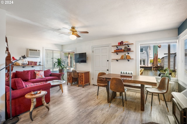 living room with hardwood / wood-style flooring, ceiling fan, a wall mounted air conditioner, and a wealth of natural light