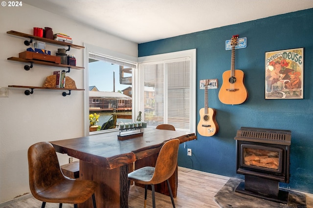 dining area with a wood stove and light wood-type flooring