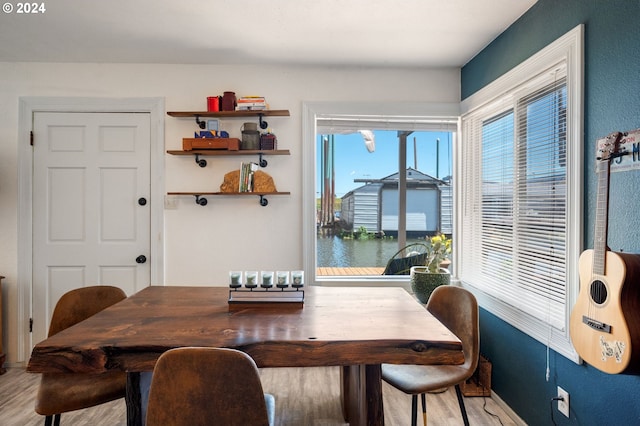 dining space featuring hardwood / wood-style floors and a water view