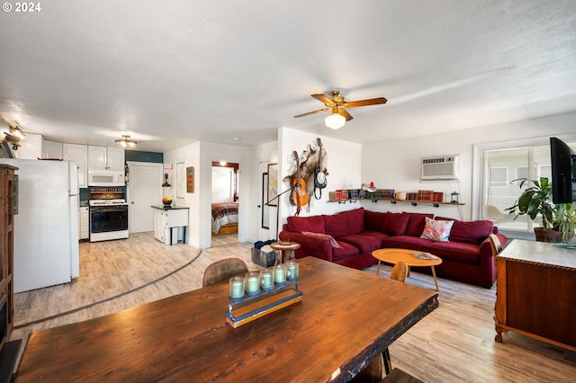 living room with a wall unit AC, ceiling fan, light hardwood / wood-style floors, and a textured ceiling