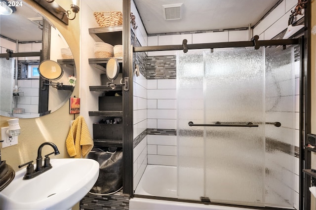 bathroom featuring a shower with door and sink