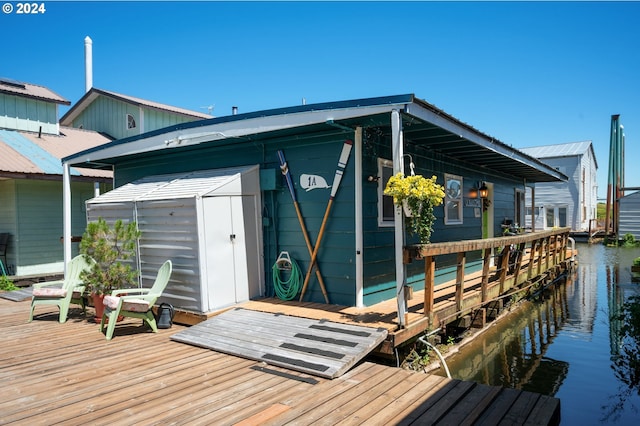 back of property with a water view and a storage shed