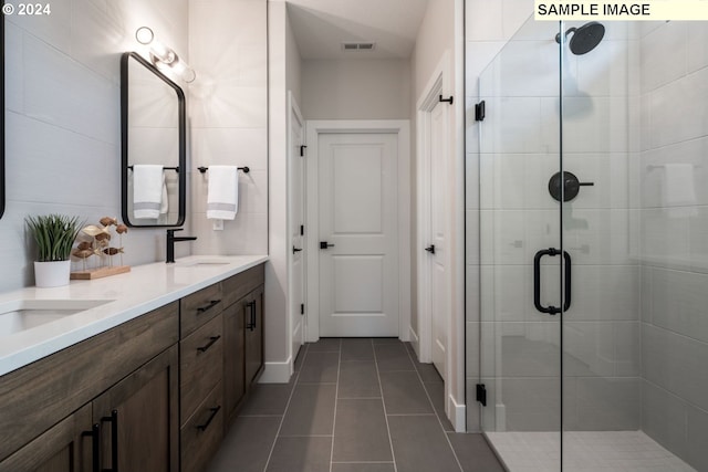 bathroom featuring tile patterned flooring, vanity, and a shower with shower door