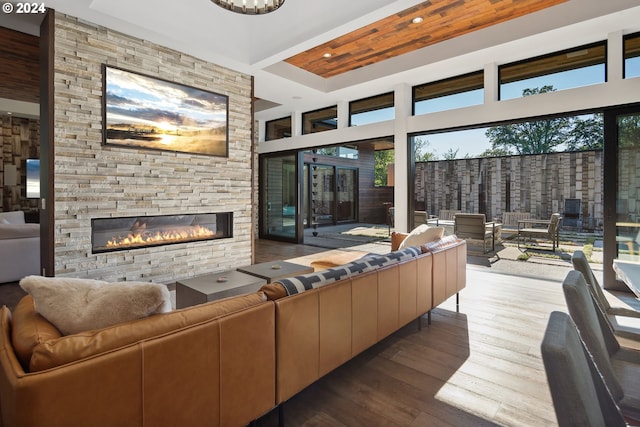 living room featuring a towering ceiling, a raised ceiling, a fireplace, and light wood-type flooring