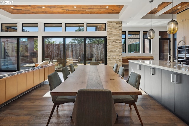 dining area with dark wood-type flooring and a raised ceiling