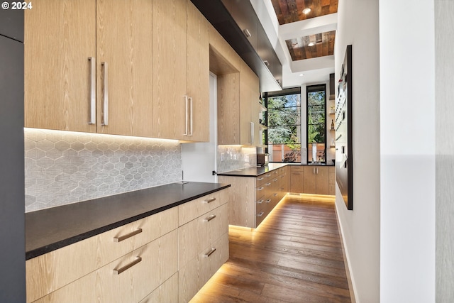 kitchen featuring light brown cabinets, beamed ceiling, dark wood-type flooring, and backsplash