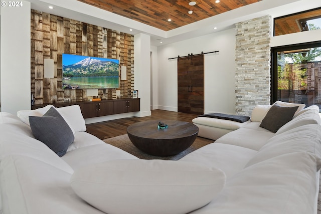 living room with a towering ceiling, a barn door, hardwood / wood-style flooring, and wooden ceiling