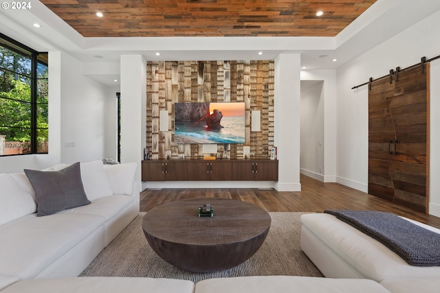 living room featuring a raised ceiling, a barn door, hardwood / wood-style flooring, and wooden ceiling