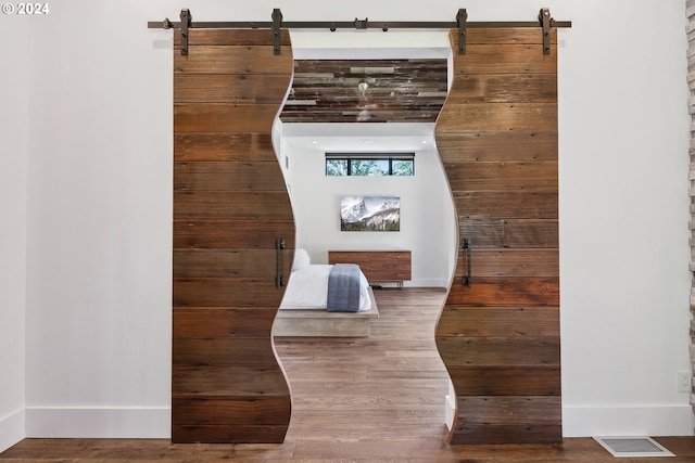 room details with visible vents, baseboards, a barn door, and wood finished floors