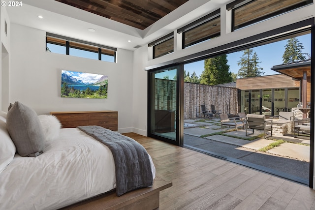 bedroom featuring access to outside, light hardwood / wood-style flooring, and a high ceiling