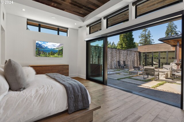 bedroom featuring baseboards, recessed lighting, a towering ceiling, wood finished floors, and access to exterior