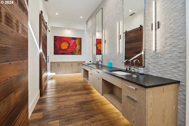 kitchen with hardwood / wood-style floors, a barn door, sink, and tasteful backsplash