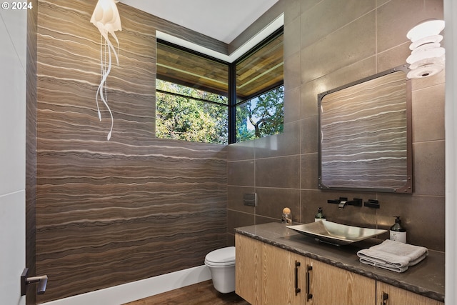 bathroom with tile walls, vanity, hardwood / wood-style floors, and toilet