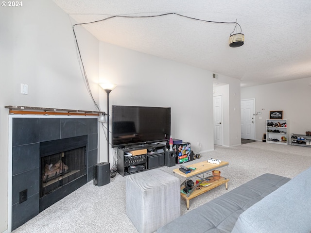 living room with a tiled fireplace, carpet floors, and a textured ceiling